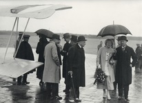 350792 Afbeelding van Prinses Juliana en een aantal hoogwaardigheidsbekleders, wachtend in de regen bij een vliegtuig ...